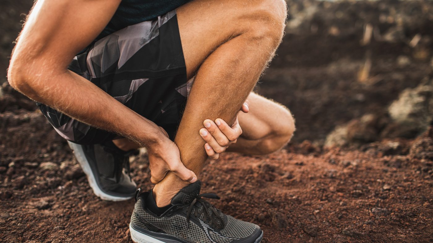 A trail runner holding the back of an ankle