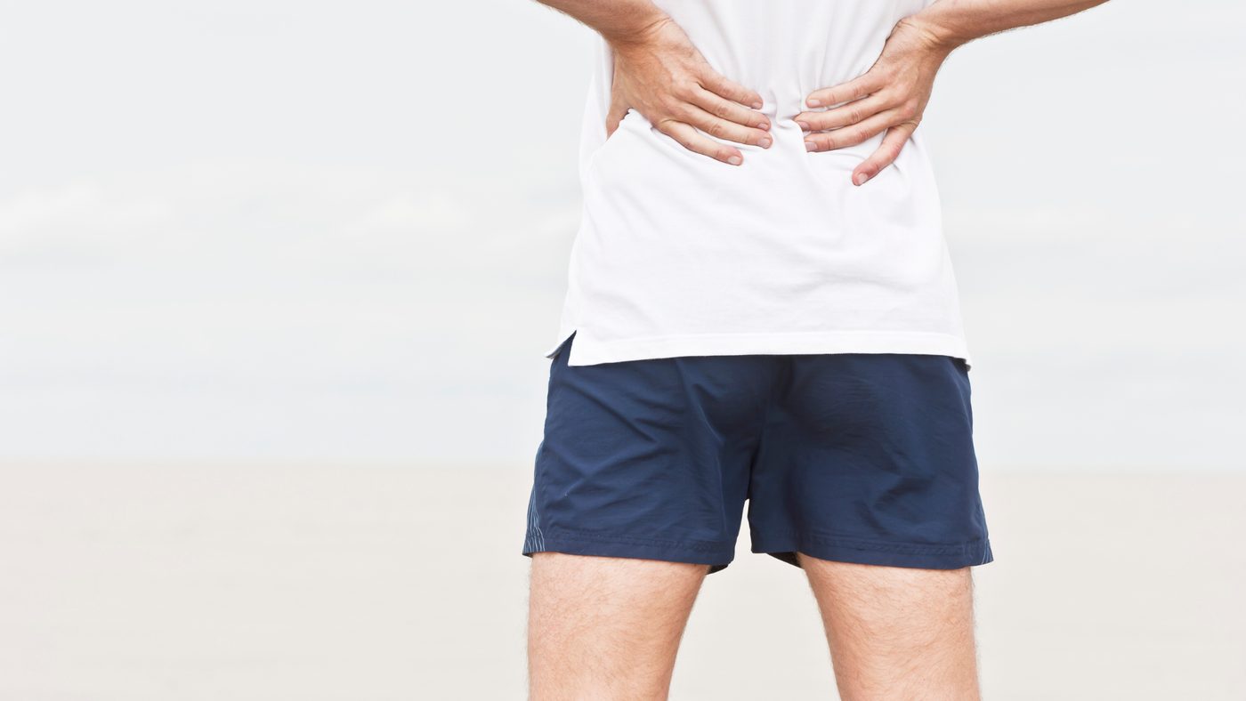 A person holding their lower back with both hands